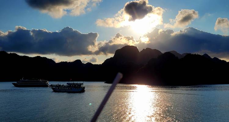 Bateaux flottant sur l'eau réfléchissante sous un coucher de soleil dramatique.