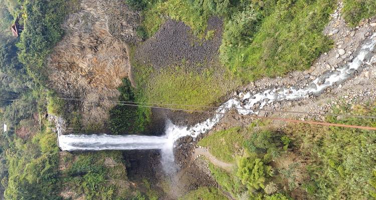 Grande cascade dégringolant le long des rochers dans une zone forestière luxuriante.