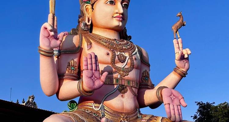 Statue colorée d'une divinité contre un ciel bleu clair.