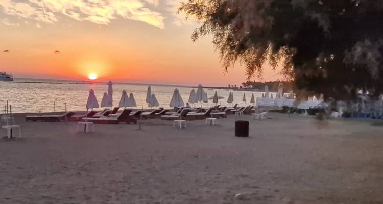Plage avec parasols et chaises longues au coucher du soleil.