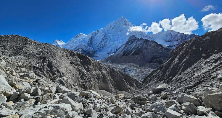 Terrain rocheux menant à d'imposantes montagnes couvertes de neige.