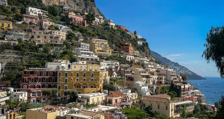 Ville colorée à flanc de colline avec des maisons serrées les unes contre les autres, surplombant la mer.
