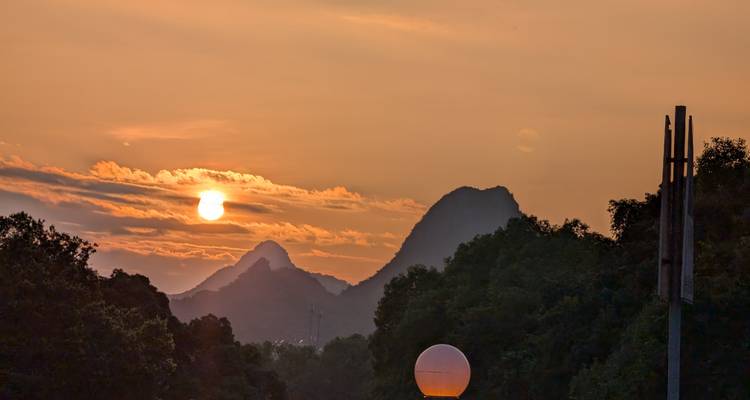 Una puesta de sol pintoresca con montañas y árboles en silueta.