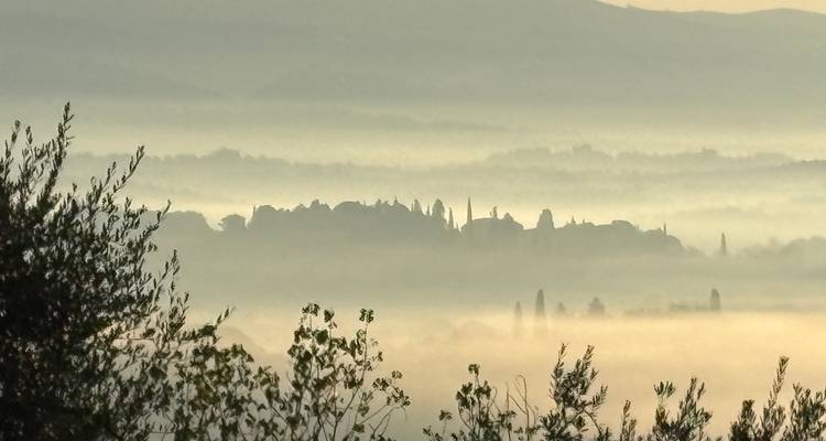 Un paysage brumeux et atmosphérique avec une ville en silhouette.