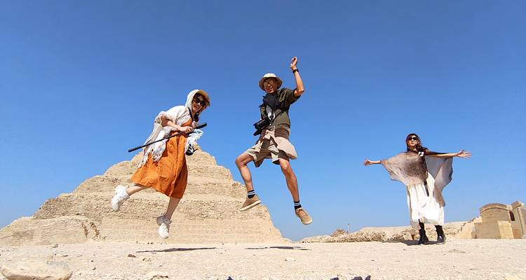 Group jumping in front of a pyramid under a clear blue sky.