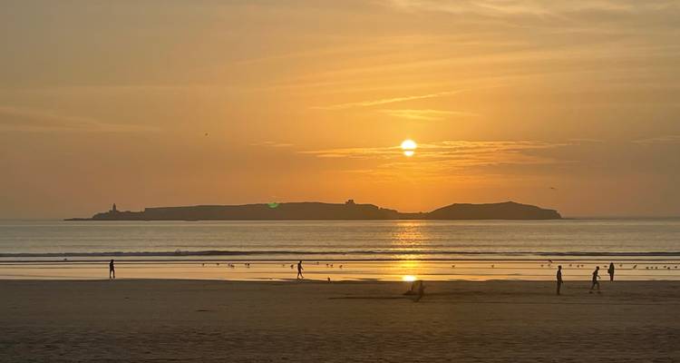 People on a beach during a golden sunset.