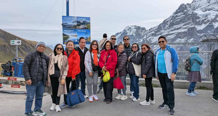 Groupe de personnes posant devant des montagnes enneigées.