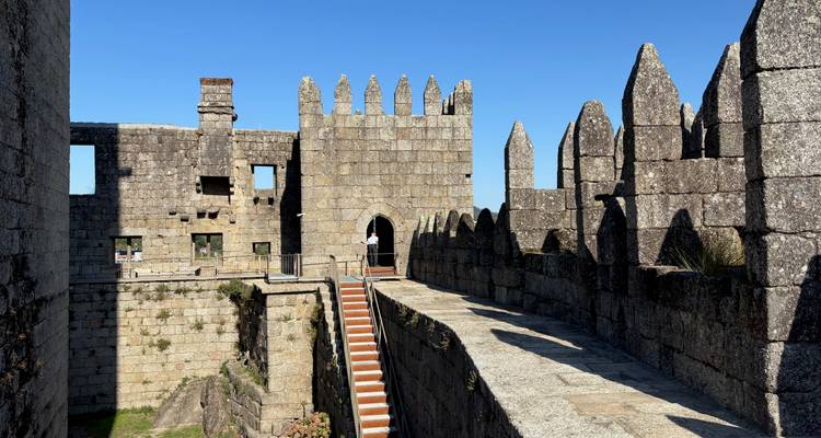Stone-walled structure with lookout points under a blue sky.