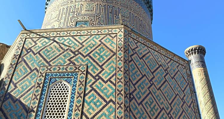 Close-up of an ornately tiled tower under a blue sky.