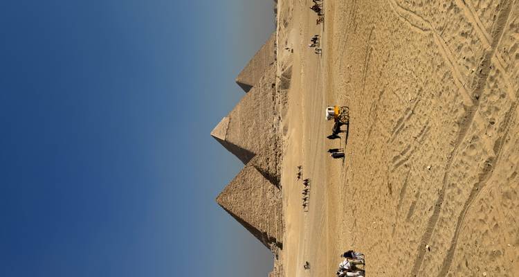 Pyramides de Gizeh avec des touristes et des chameaux au premier plan.