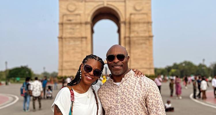 Couple posing in front of a large arch monument.