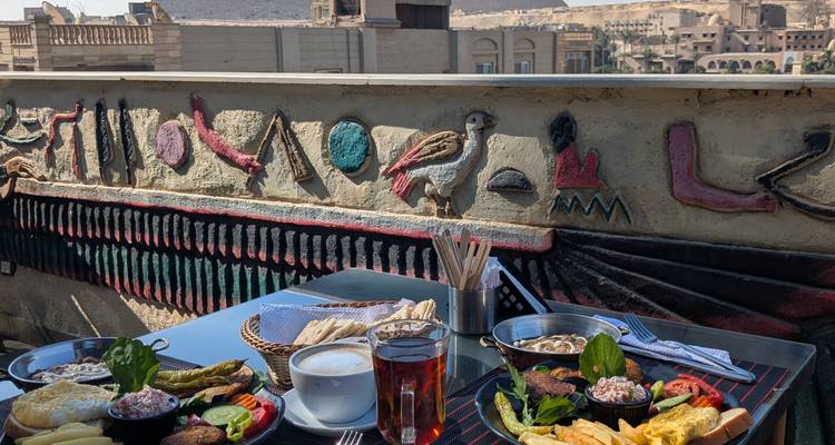 Plate of food and drink next to a wall with Egyptian hieroglyphs.