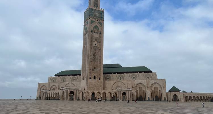 Große Moschee mit einem hohen Minarett vor einem teilweise bewölkten Himmel.