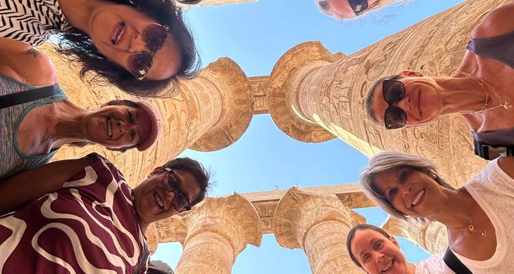 Group of people looking upwards with ancient stone columns towering above.