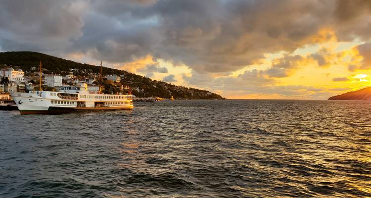 Ferry en un cuerpo de agua con vista de atardecer.