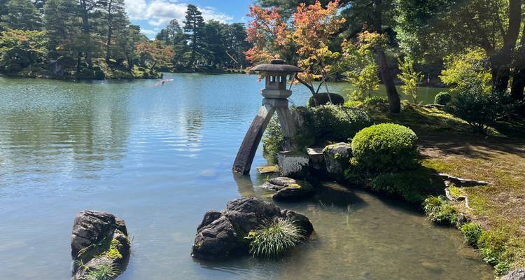 Vue sereine sur le lac avec lanterne en pierre et feuillage.