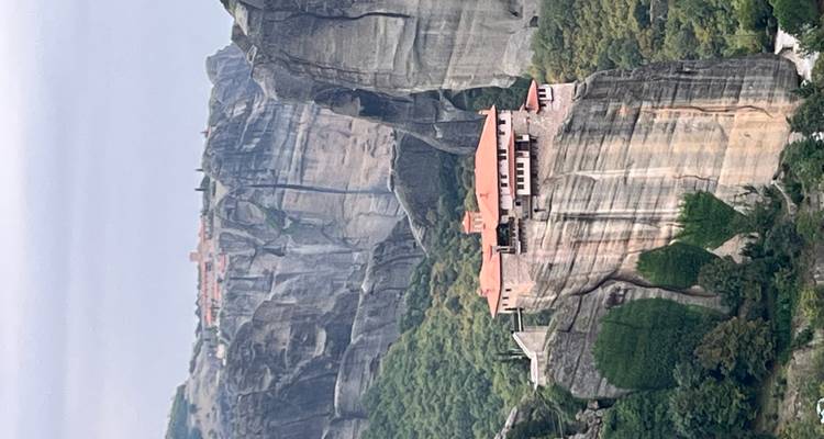 Monastère sur une falaise rocheuse avec de la verdure autour.