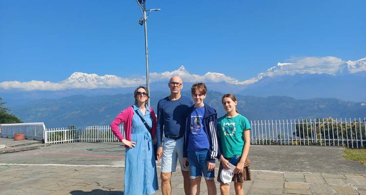Une famille posant avec un arrière-plan montagneux sous un ciel dégagé.