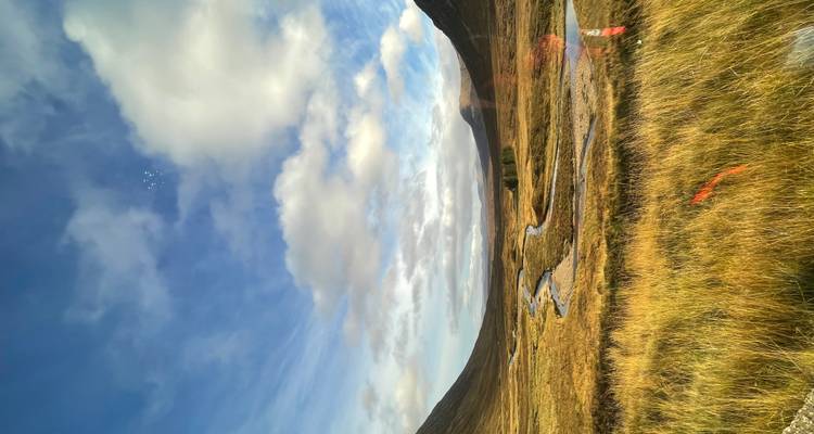 Vue panoramique d'une vallée avec une rivière sinueuse et des montagnes au loin.