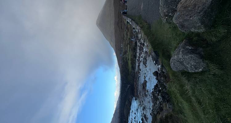 Rivière et collines sous un ciel nuageux, avec des gens qui explorent.
