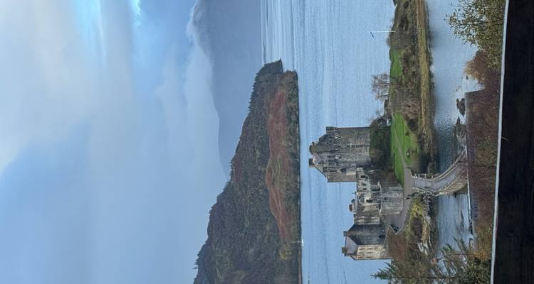 Vue panoramique du château d'Eilean Donan par une journée avec des nuages dramatiques.