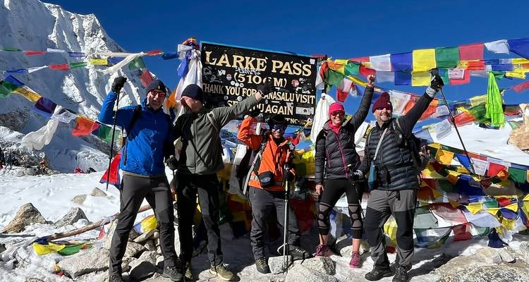Groep trekkers die vieren bij Larke Pass met kleurrijke gebedsvlaggen.