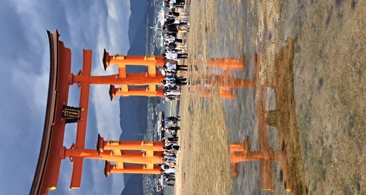 Touristen, die vor dem Tor des Itsukushima-Schreins spazieren gehen.