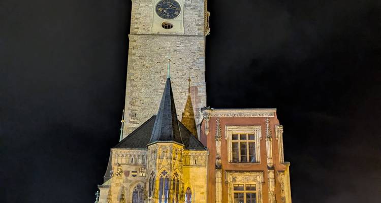 Bâtiment historique avec tour d'horloge illuminé la nuit.