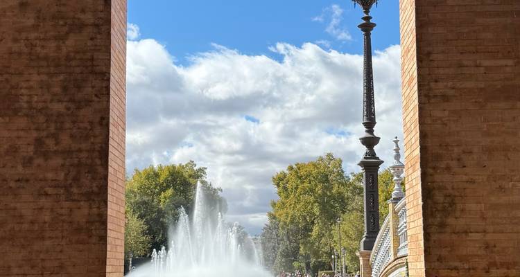 Fuente y farola vistas a través de un gran arco de ladrillo.