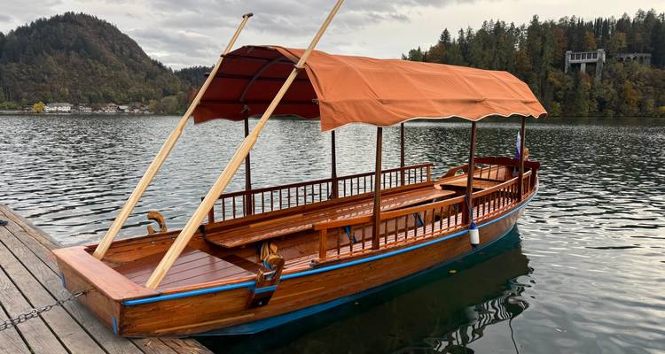 Houten boot afgemeerd bij het meer met bergen op de achtergrond.
