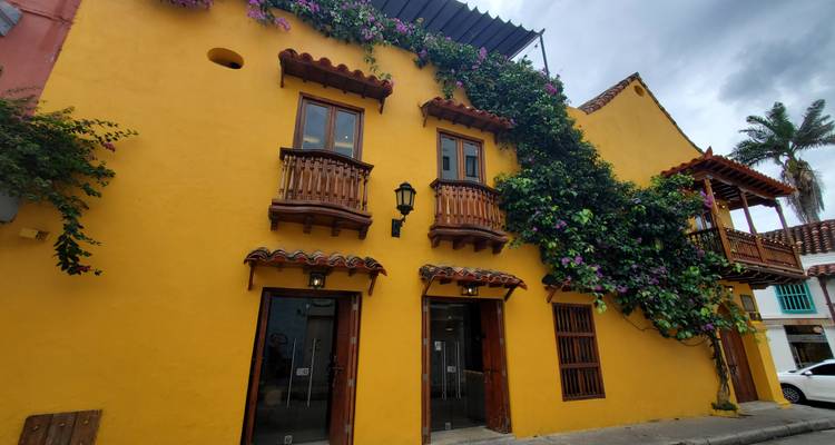 Kleurrijk koloniaal gebouw met bloemen die tegen de gevel omhoogklimmen.