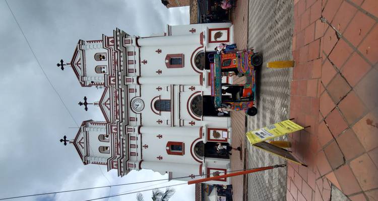 Witte kerk met rode accenten en een tuk-tuk die voorbijrijdt.