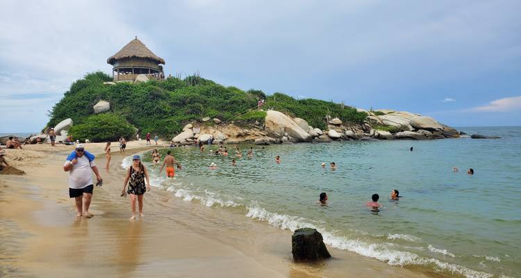 Strandscène met mensen die zwemmen en een hut op een heuvel.