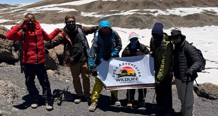 Groupe de randonneurs posant avec une bannière dans une zone montagneuse.
