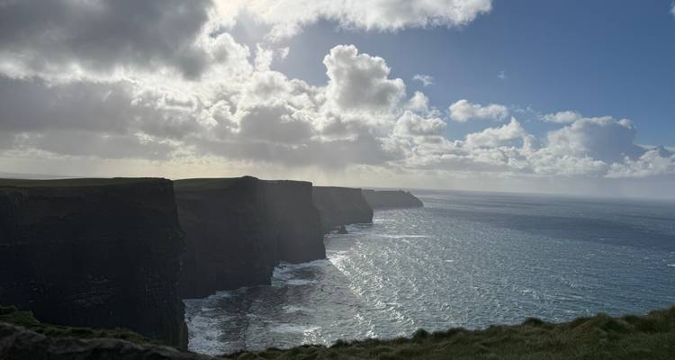 Dramatisch uitzicht op kliffen die de oceaan ontmoeten met een bewolkte lucht erboven.