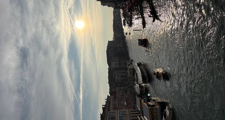 Canal veneciano al atardecer con barcas y edificios reflejados en el agua.