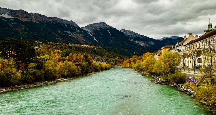 Rivier die door een stad stroomt met bergen op de achtergrond.