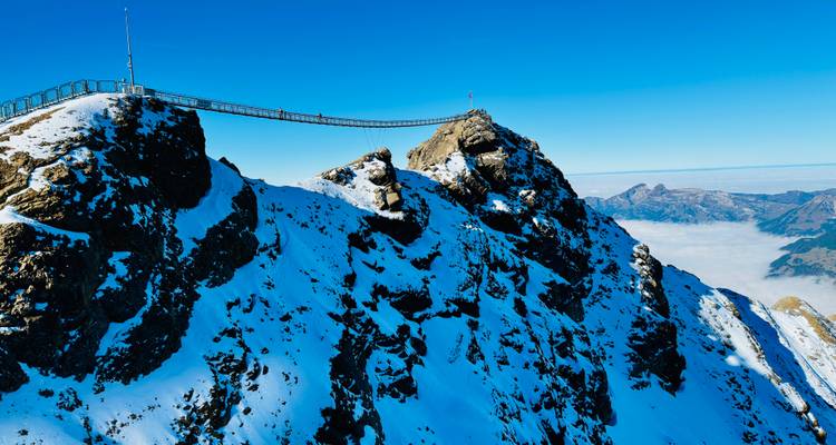 Winterliche Berglandschaft mit einer Brücke, die Gipfel verbindet.