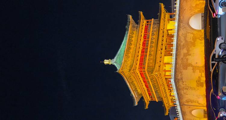 Bâtiment traditionnel chinois illuminé la nuit.