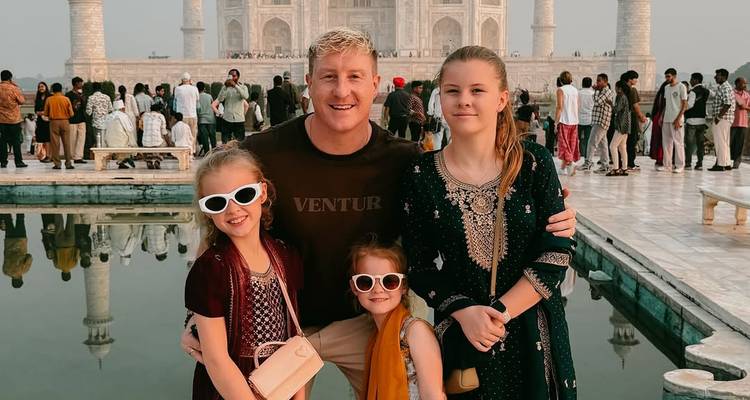 Une famille posant devant un bassin réfléchissant avec le Taj Mahal en arrière-plan.