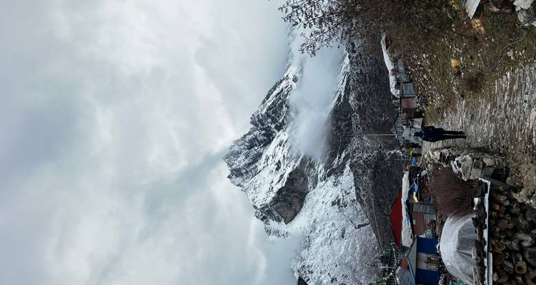 Personne marchant le long d'un sentier vers des sommets montagneux enneigés.