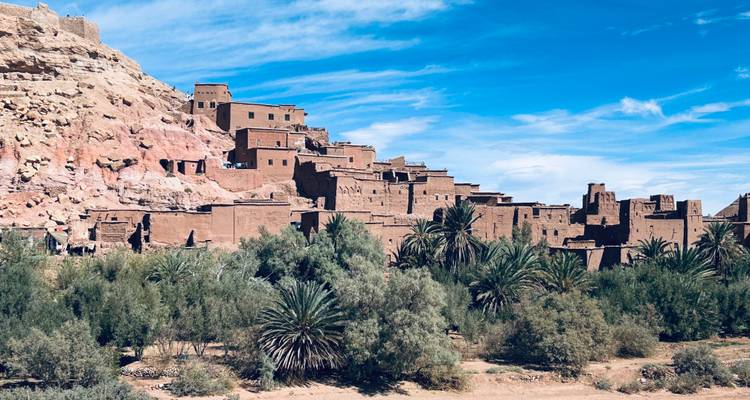 Ait Benhaddou con palmeras en primer plano.