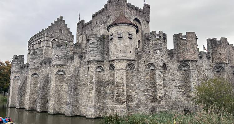 Un château médiéval avec des murs de pierre, situé près de l'eau.