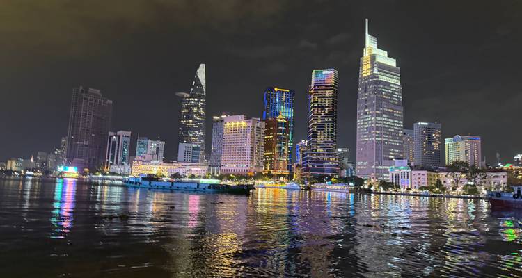 Stadsskyline bij nacht met verlichte gebouwen en reflecties op het water.