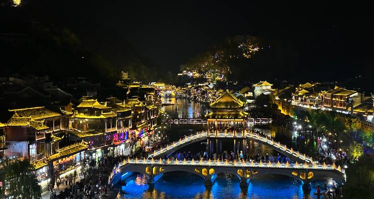 Architecture chinoise traditionnelle illuminée au-dessus d'une rivière la nuit.