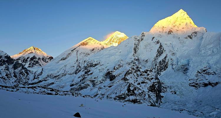 Snow-capped mountains with a golden glow at sunrise.