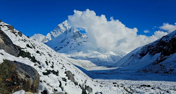 Paisaje montañoso nevado con cielo azul claro y un valle.