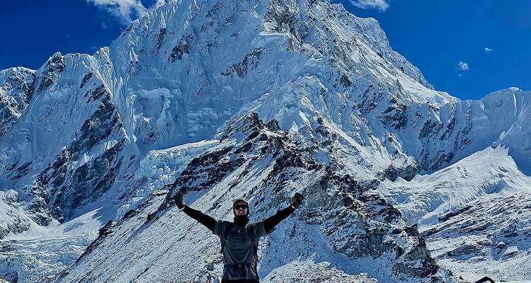 Persona celebrando frente a una vasta montaña nevada.