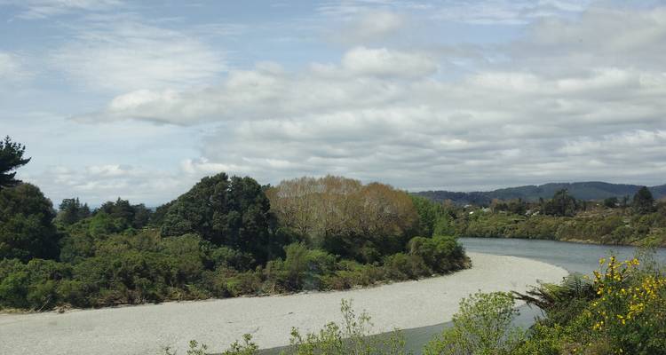 Río serpenteante con bosque y colinas al fondo.