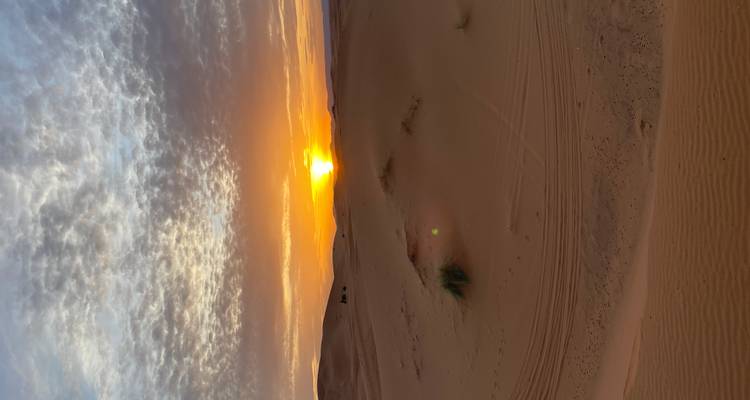 Coucher de soleil sur un paysage désertique sablonneux.